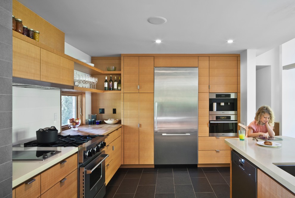 Trendy l-shaped kitchen photo in Toronto with an undermount sink, flat-panel cabinets, light wood cabinets, white backsplash, stainless steel appliances and an island