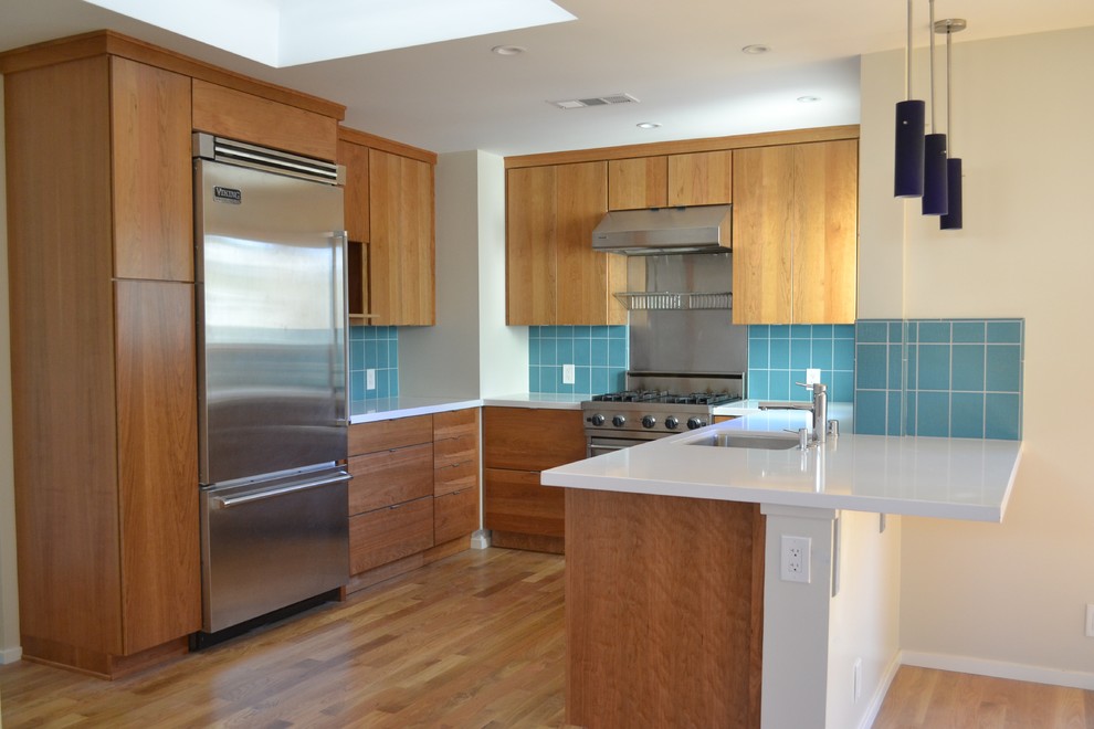 サンフランシスコにある高級な小さなエクレクティックスタイルのおしゃれなキッチン (アンダーカウンターシンク、フラットパネル扉のキャビネット、中間色木目調キャビネット、クオーツストーンカウンター、青いキッチンパネル、セラミックタイルのキッチンパネル、シルバーの調理設備、塗装フローリング、茶色い床、白いキッチンカウンター) の写真