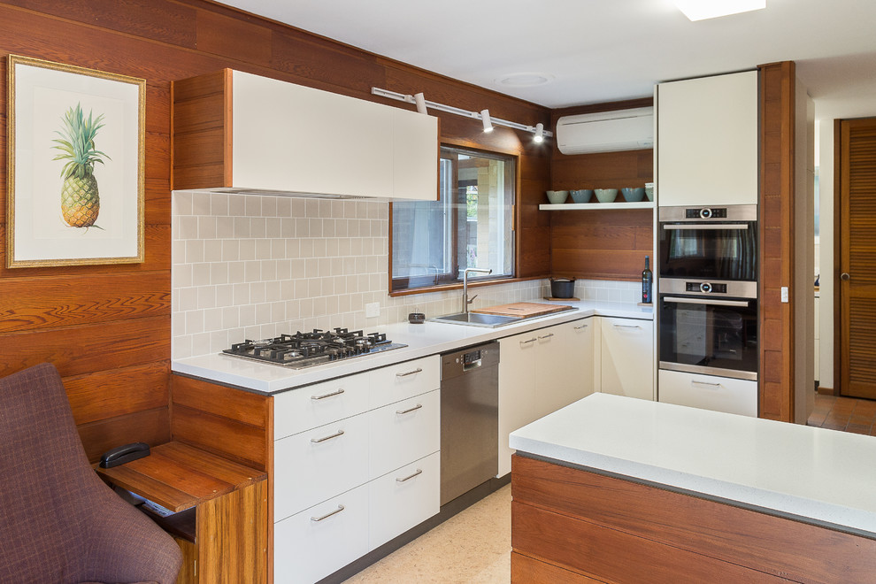 Exempel på ett mellanstort 50 tals vit vitt kök, med en dubbel diskho, bänkskiva i kvarts, beige stänkskydd, stänkskydd i keramik, rostfria vitvaror, korkgolv och beiget golv