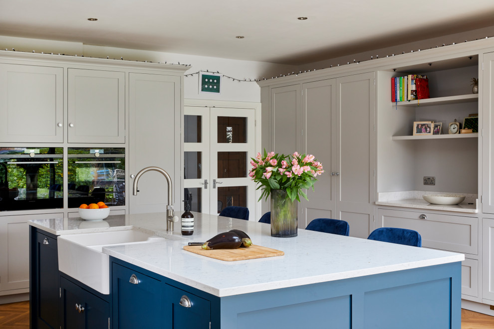 Large contemporary u-shaped open plan kitchen in Kent with a double-bowl sink, an island and white worktops.