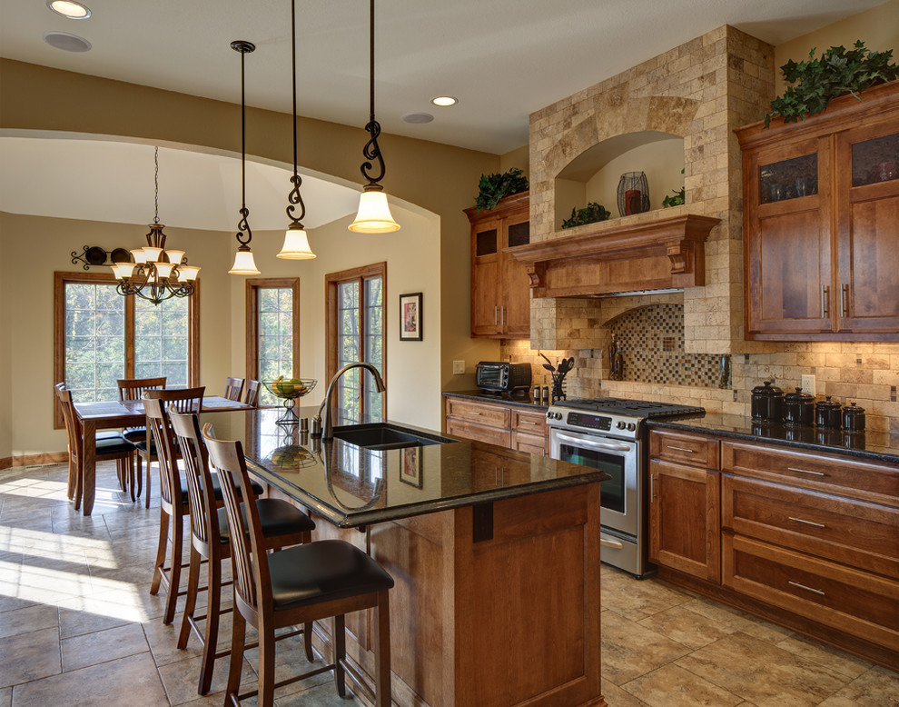 Large tuscan ceramic tile eat-in kitchen photo in Milwaukee with a double-bowl sink, recessed-panel cabinets, medium tone wood cabinets, beige backsplash, stainless steel appliances, an island, granite countertops and stone tile backsplash