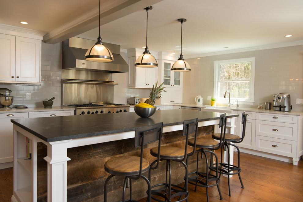 Inspiration for a mid-sized modern l-shaped dark wood floor kitchen remodel in Boston with a farmhouse sink, shaker cabinets, white cabinets, solid surface countertops, gray backsplash, subway tile backsplash, stainless steel appliances and an island
