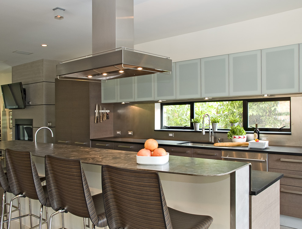 Imagen de cocina contemporánea con electrodomésticos de acero inoxidable, fregadero bajoencimera, armarios con paneles lisos, puertas de armario marrones y barras de cocina