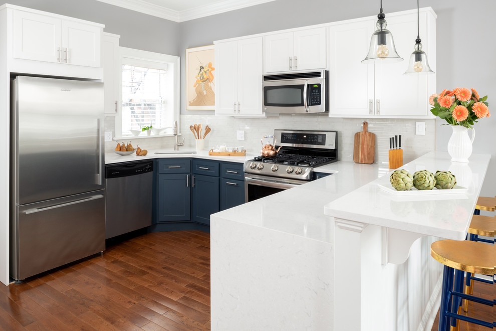 Example of a mid-sized trendy u-shaped dark wood floor and brown floor eat-in kitchen design in Philadelphia with a single-bowl sink, flat-panel cabinets, blue cabinets, quartzite countertops, white backsplash, ceramic backsplash, stainless steel appliances and white countertops