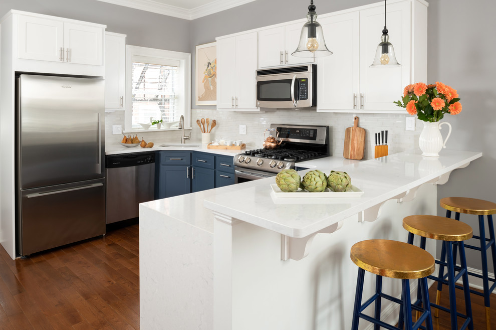 Foto på ett mellanstort funkis vit kök, med en enkel diskho, släta luckor, blå skåp, bänkskiva i kvartsit, vitt stänkskydd, stänkskydd i keramik, rostfria vitvaror, mörkt trägolv och brunt golv