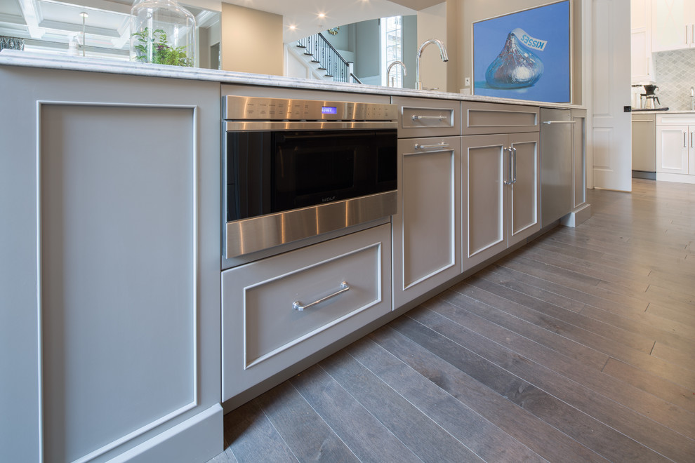 Inspiration for a large traditional kitchen/diner in Philadelphia with multiple islands, recessed-panel cabinets, grey cabinets, marble worktops, grey splashback, mosaic tiled splashback, stainless steel appliances, an integrated sink and medium hardwood flooring.