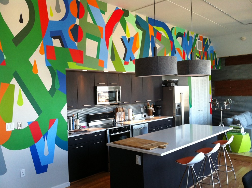 На фото: параллельная кухня-гостиная в современном стиле с плоскими фасадами, черными фасадами, фартуком цвета металлик, техникой из нержавеющей стали и обоями на стенах с