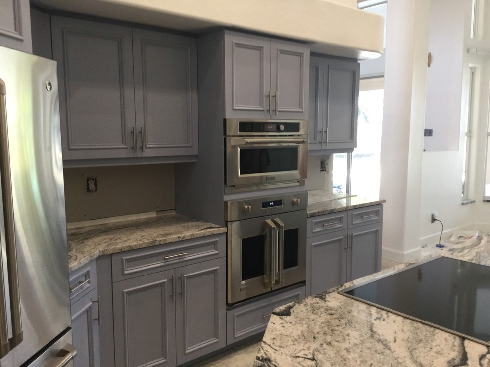 Mid-sized trendy galley ceramic tile eat-in kitchen photo in Miami with an undermount sink, flat-panel cabinets, blue cabinets, granite countertops, white backsplash, stone tile backsplash, stainless steel appliances and an island