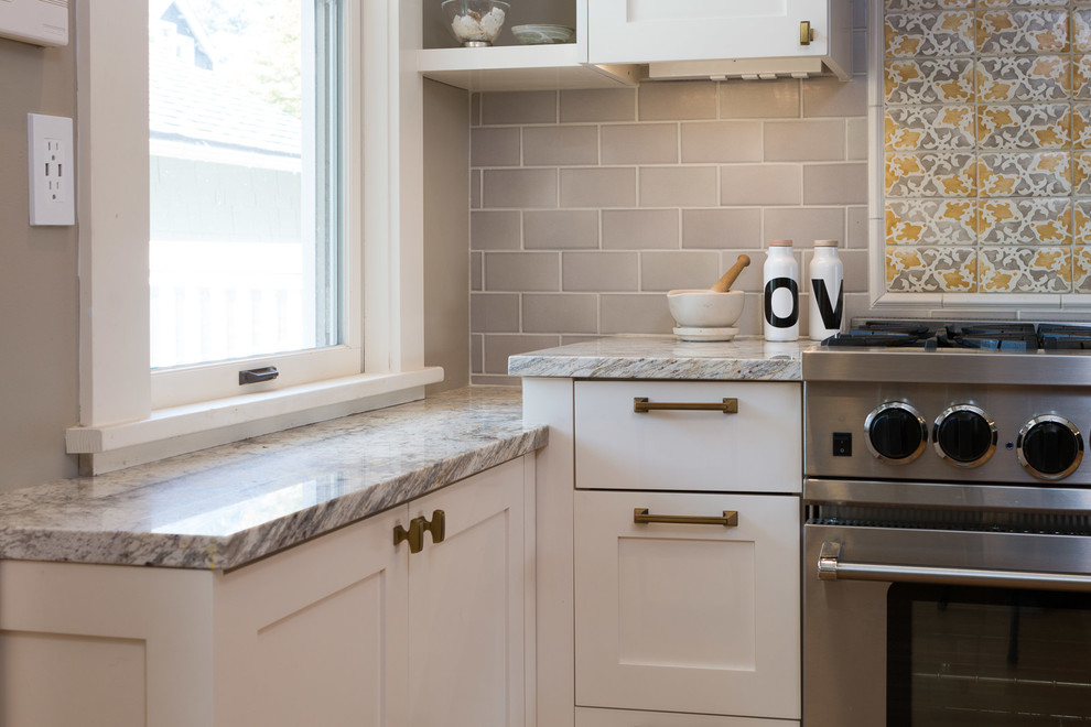 Bild på ett mellanstort vintage grå grått kök, med en undermonterad diskho, luckor med infälld panel, vita skåp, marmorbänkskiva, grått stänkskydd, stänkskydd i tunnelbanekakel, rostfria vitvaror, mörkt trägolv, en köksö och brunt golv