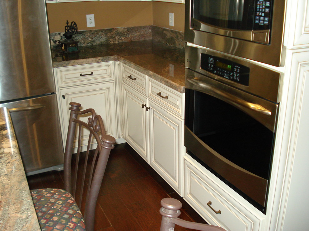Inredning av ett klassiskt mellanstort kök, med en undermonterad diskho, luckor med upphöjd panel, skåp i slitet trä, rostfria vitvaror och en köksö