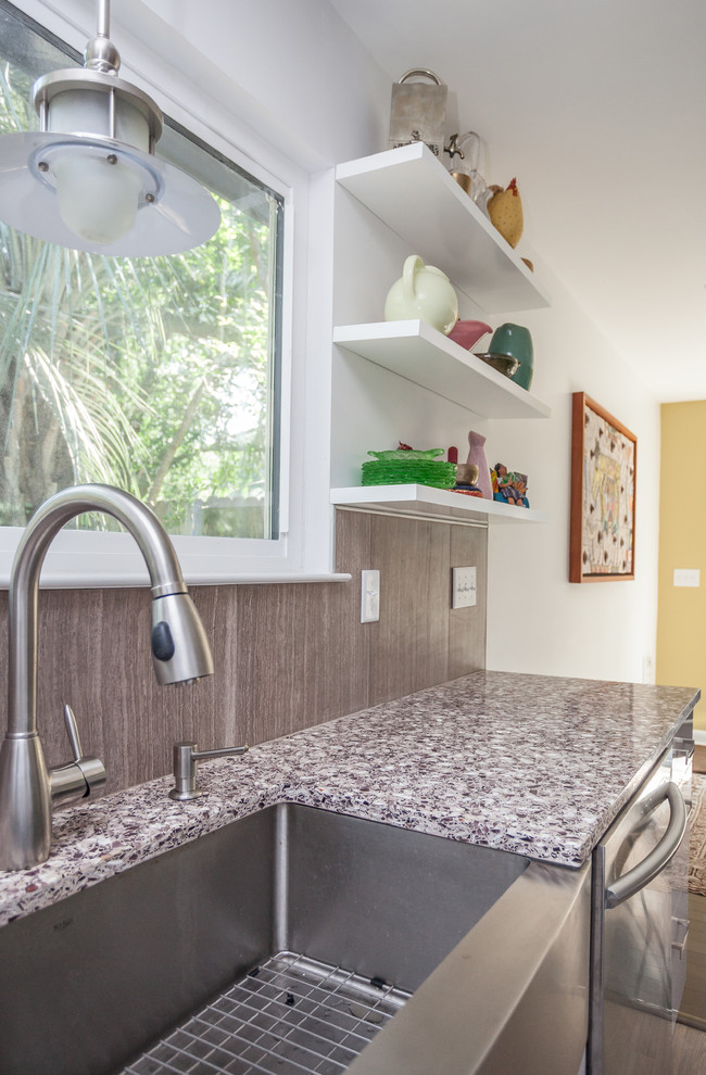 Modern inredning av ett stort kök, med en rustik diskho, vita skåp, rostfria vitvaror, släta luckor, bänkskiva i återvunnet glas, brunt stänkskydd, stänkskydd i cementkakel och klinkergolv i porslin