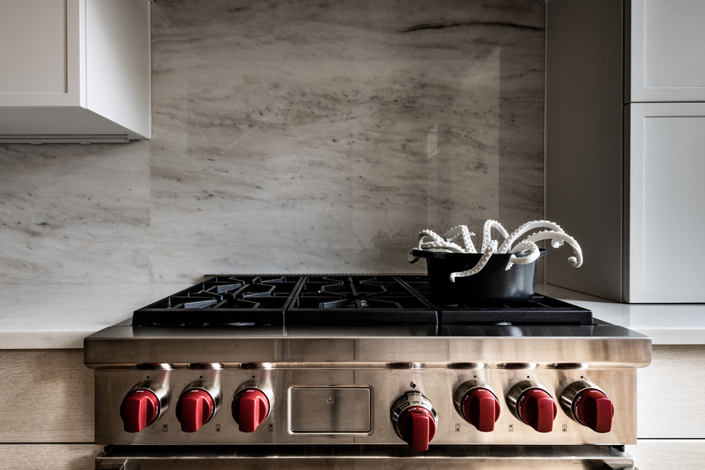 Foto di una cucina moderna di medie dimensioni con lavello a vasca singola, ante lisce, ante in legno chiaro, top in marmo, paraspruzzi grigio, paraspruzzi in marmo, elettrodomestici in acciaio inossidabile, parquet scuro, pavimento marrone e top bianco