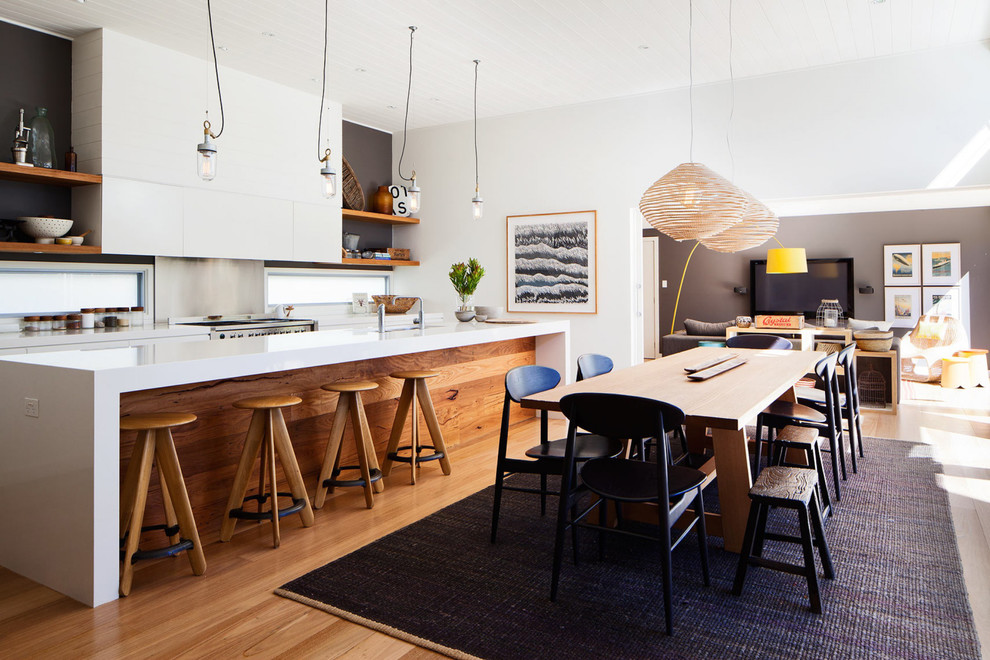 Eat-in kitchen - mid-sized contemporary galley medium tone wood floor eat-in kitchen idea in Sydney with flat-panel cabinets, white cabinets, metallic backsplash, stainless steel appliances and an island