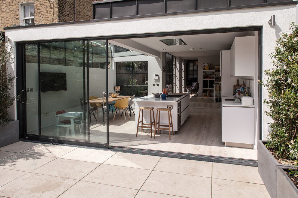 Offene, Zweizeilige Moderne Küche mit Unterbauwaschbecken, flächenbündigen Schrankfronten, weißen Schränken, Küchenrückwand in Weiß, hellem Holzboden und Kücheninsel in London
