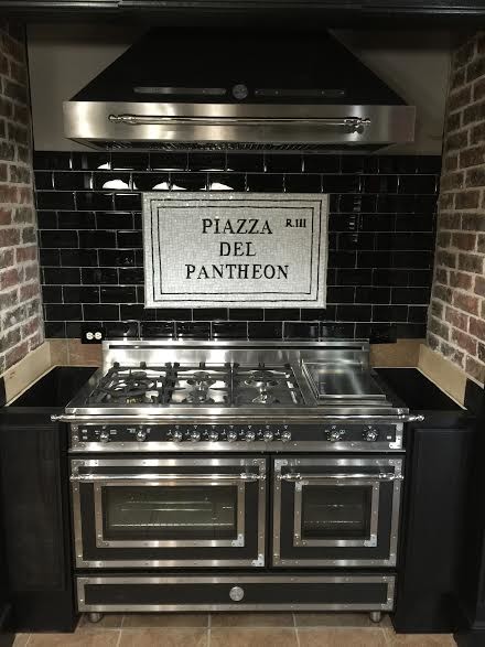 Example of a mid-sized tuscan single-wall porcelain tile eat-in kitchen design in Boston with raised-panel cabinets, black cabinets, black backsplash, glass tile backsplash and stainless steel appliances