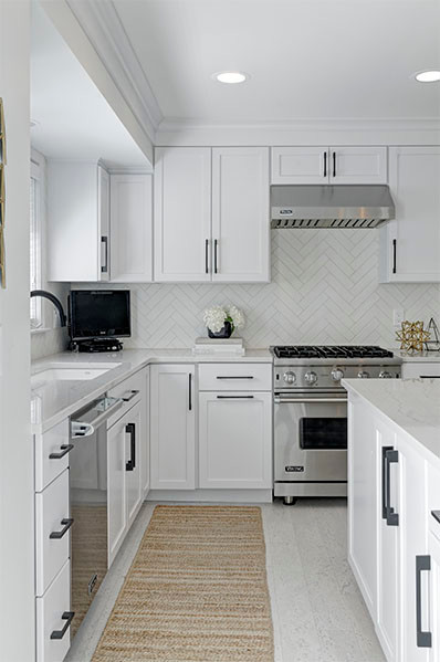 Eklektisk inredning av ett mellanstort kök, med en undermonterad diskho, skåp i shakerstil, vita skåp, bänkskiva i kvartsit, vitt stänkskydd, stänkskydd i keramik, rostfria vitvaror, korkgolv, en köksö och vitt golv
