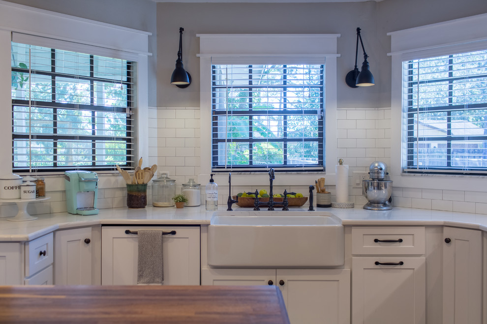 Inspiration for a medium sized rural l-shaped kitchen/diner in Tampa with a belfast sink, shaker cabinets, white cabinets, wood worktops, grey splashback, marble splashback, integrated appliances, medium hardwood flooring, an island, brown floors and brown worktops.