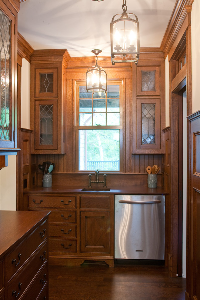 Modelo de cocina clásica de roble con armarios tipo vitrina, puertas de armario de madera oscura, encimera de madera y electrodomésticos de acero inoxidable