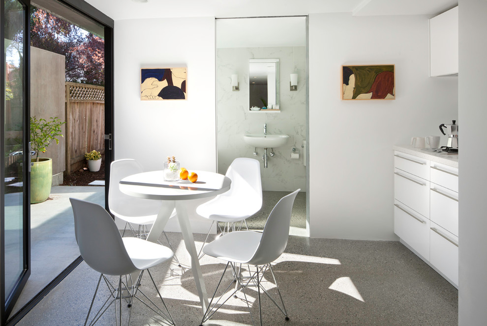 Cette image montre une cuisine américaine linéaire minimaliste avec un placard à porte plane et des portes de placard blanches.