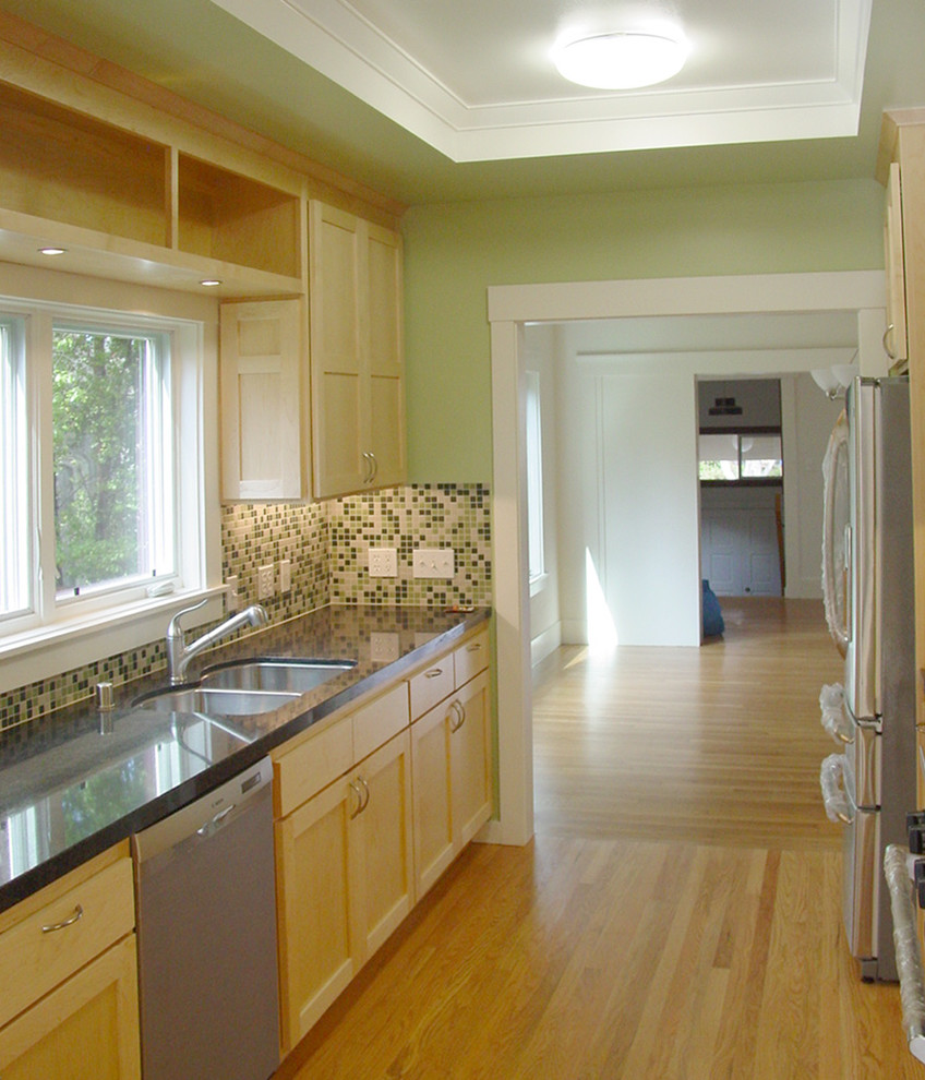 Mid-sized trendy galley medium tone wood floor and yellow floor enclosed kitchen photo in San Francisco with a double-bowl sink, shaker cabinets, light wood cabinets, granite countertops, multicolored backsplash, glass tile backsplash, stainless steel appliances and no island