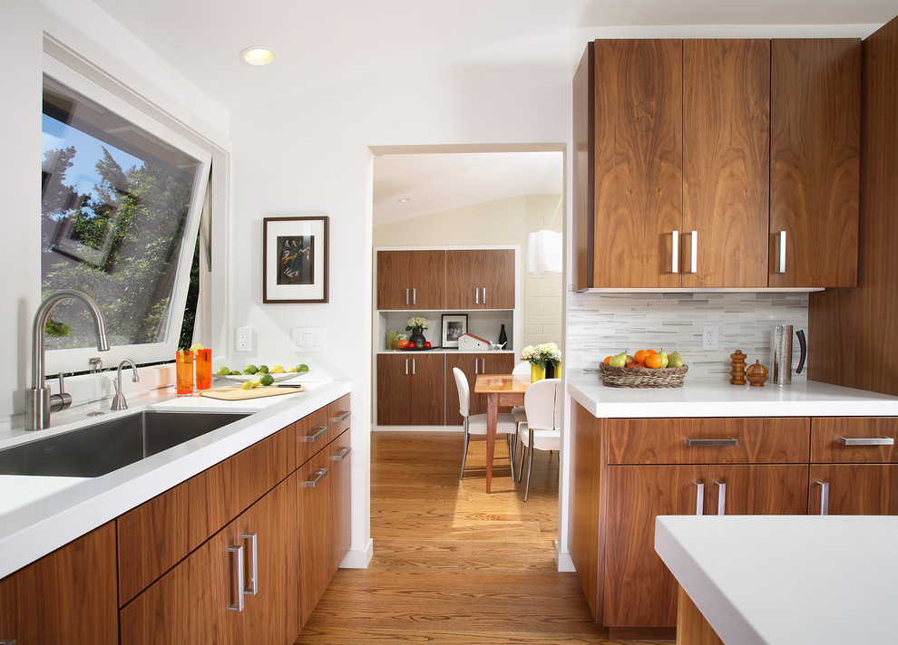 Moderne Küche mit Unterbauwaschbecken, flächenbündigen Schrankfronten, hellbraunen Holzschränken, Küchenrückwand in Weiß, braunem Holzboden und Kücheninsel in San Francisco