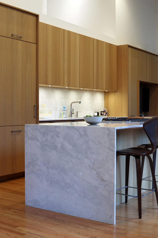 Exempel på ett modernt kök, med en undermonterad diskho, släta luckor, skåp i ljust trä, marmorbänkskiva, vitt stänkskydd, integrerade vitvaror, ljust trägolv och en köksö