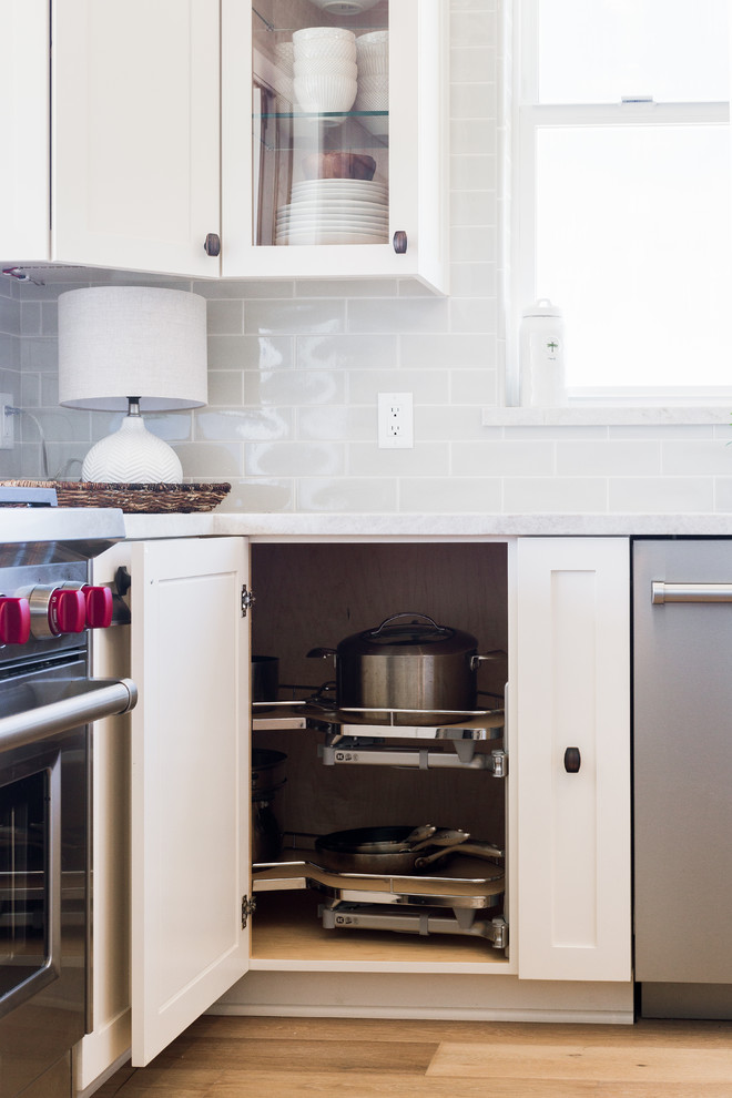 Foto de cocina costera de tamaño medio con armarios estilo shaker, puertas de armario blancas, encimera de acrílico y una isla