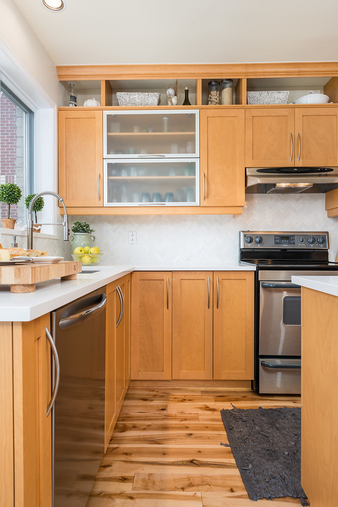 Aménagement d'une cuisine classique en L avec un placard à porte shaker, des portes de placard marrons, une crédence blanche, un électroménager en acier inoxydable, un sol en bois brun et un sol marron.