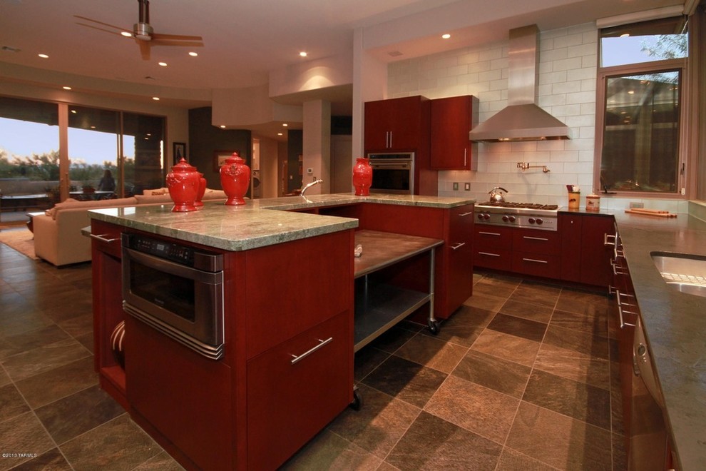 Modern inredning av ett stort kök, med en undermonterad diskho, släta luckor, skåp i mörkt trä, granitbänkskiva, blått stänkskydd, stänkskydd i glaskakel, rostfria vitvaror, travertin golv och en köksö