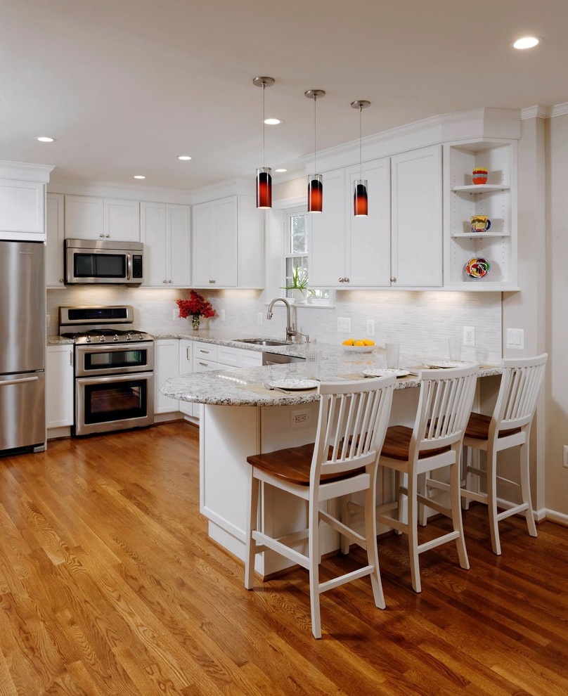 Example of a large classic l-shaped medium tone wood floor open concept kitchen design in DC Metro with an undermount sink, recessed-panel cabinets, white cabinets, granite countertops, gray backsplash, matchstick tile backsplash, stainless steel appliances and a peninsula