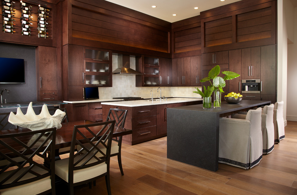 Klassische Wohnküche in L-Form mit flächenbündigen Schrankfronten, dunklen Holzschränken, Küchenrückwand in Weiß, Elektrogeräten mit Frontblende, braunem Holzboden und zwei Kücheninseln in Miami
