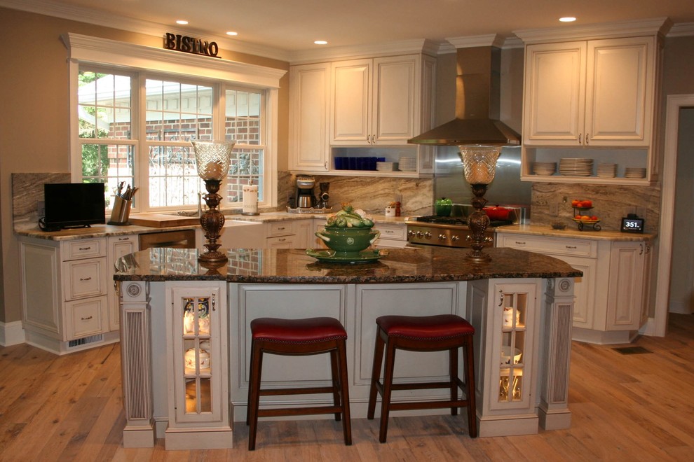 Example of a large french country l-shaped light wood floor eat-in kitchen design in Raleigh with a farmhouse sink, raised-panel cabinets, distressed cabinets, quartzite countertops, gray backsplash, stone slab backsplash, stainless steel appliances and an island