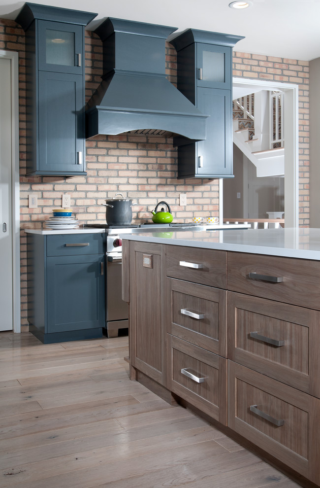 Exempel på ett mellanstort klassiskt kök, med en undermonterad diskho, luckor med infälld panel, blå skåp, bänkskiva i kvartsit, flerfärgad stänkskydd, stänkskydd i tegel, rostfria vitvaror, ljust trägolv och en köksö