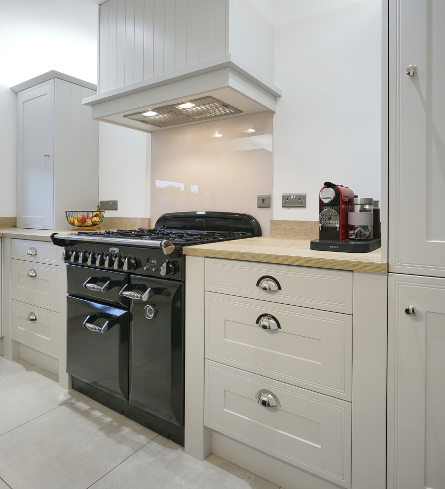 Enclosed kitchen - small traditional l-shaped ceramic tile and beige floor enclosed kitchen idea in Belfast with a single-bowl sink, shaker cabinets, gray cabinets, laminate countertops, pink backsplash, glass sheet backsplash, black appliances, an island and brown countertops