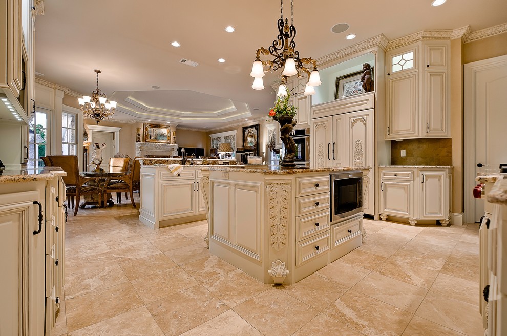 Inspiration for a large timeless travertine floor eat-in kitchen remodel in Little Rock with an undermount sink, raised-panel cabinets, distressed cabinets, granite countertops, stone tile backsplash, stainless steel appliances and two islands