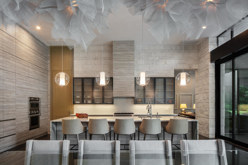 Immagine di una cucina contemporanea con lavello sottopiano, ante di vetro, ante grigie, paraspruzzi bianco, elettrodomestici in acciaio inossidabile, top grigio e pavimento nero