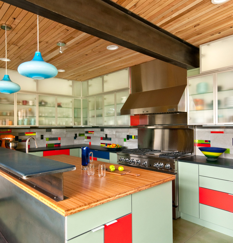 Exempel på ett stort industriellt kök, med träbänkskiva, släta luckor, gröna skåp, flerfärgad stänkskydd, betonggolv och en köksö