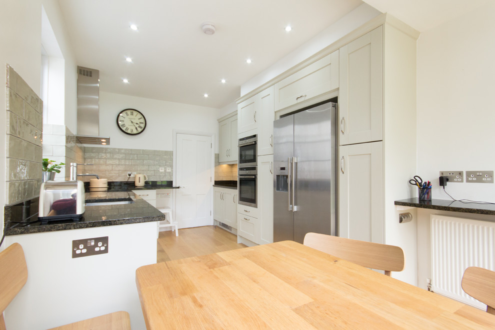 Inspiration for a medium sized contemporary galley kitchen/diner in London with a built-in sink, shaker cabinets, green cabinets, granite worktops, green splashback, porcelain splashback, stainless steel appliances, medium hardwood flooring and no island.