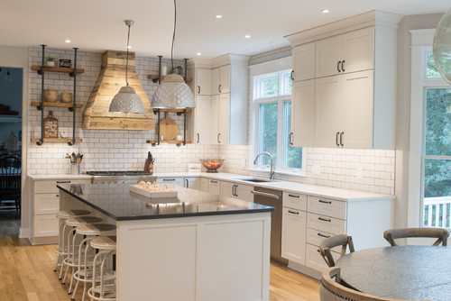 Bright kitchen with premium white shaker RTA cabinets, dark quartz island, subway tile backsplash, and wooden range hood in a Canadian home.