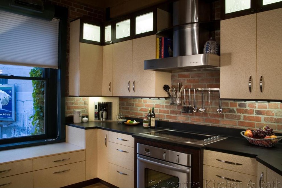 Cette image montre une cuisine bohème de taille moyenne avec un placard à porte plane, un plan de travail en surface solide, une crédence marron, une crédence en brique et un sol en bois brun.