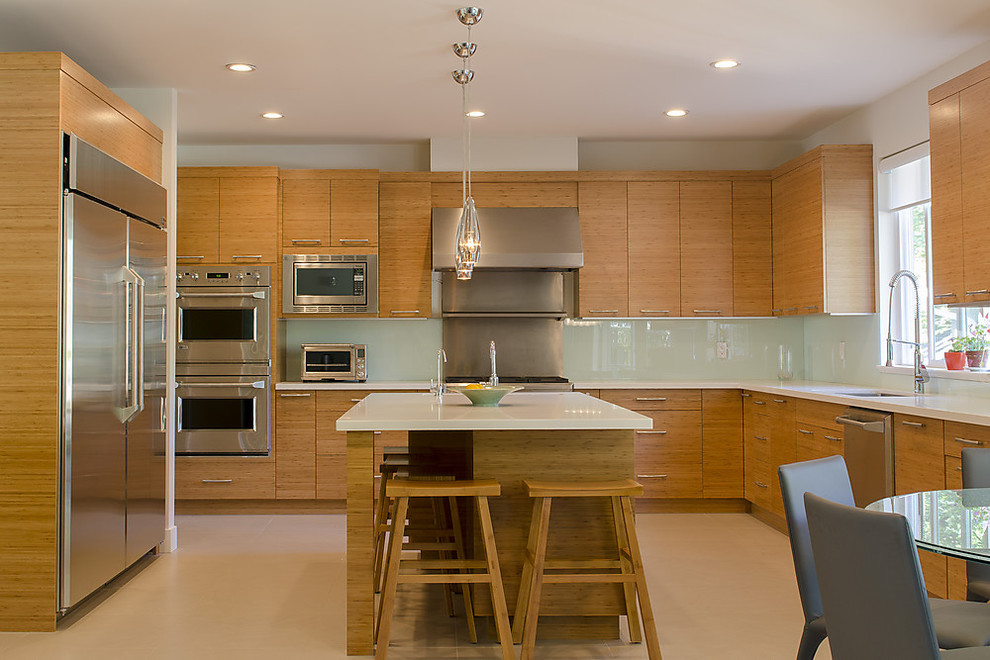 バンクーバーにあるコンテンポラリースタイルのおしゃれなキッチン (フラットパネル扉のキャビネット、淡色木目調キャビネット、ガラス板のキッチンパネル、シルバーの調理設備) の写真