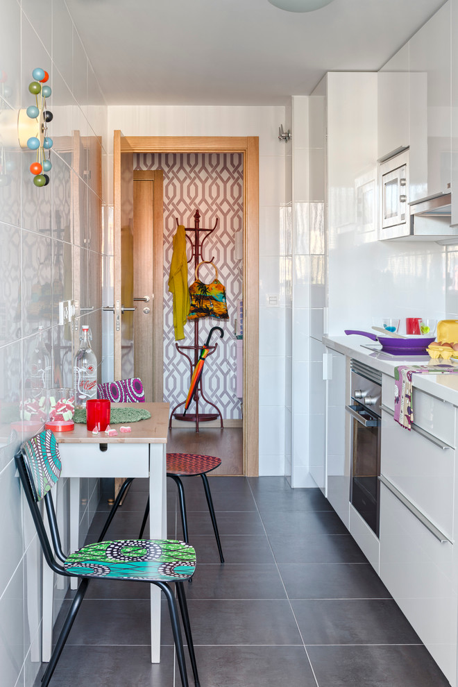 Small bohemian single-wall kitchen/diner in Malaga with flat-panel cabinets, white cabinets, white splashback, stainless steel appliances, slate flooring, no island and composite countertops.