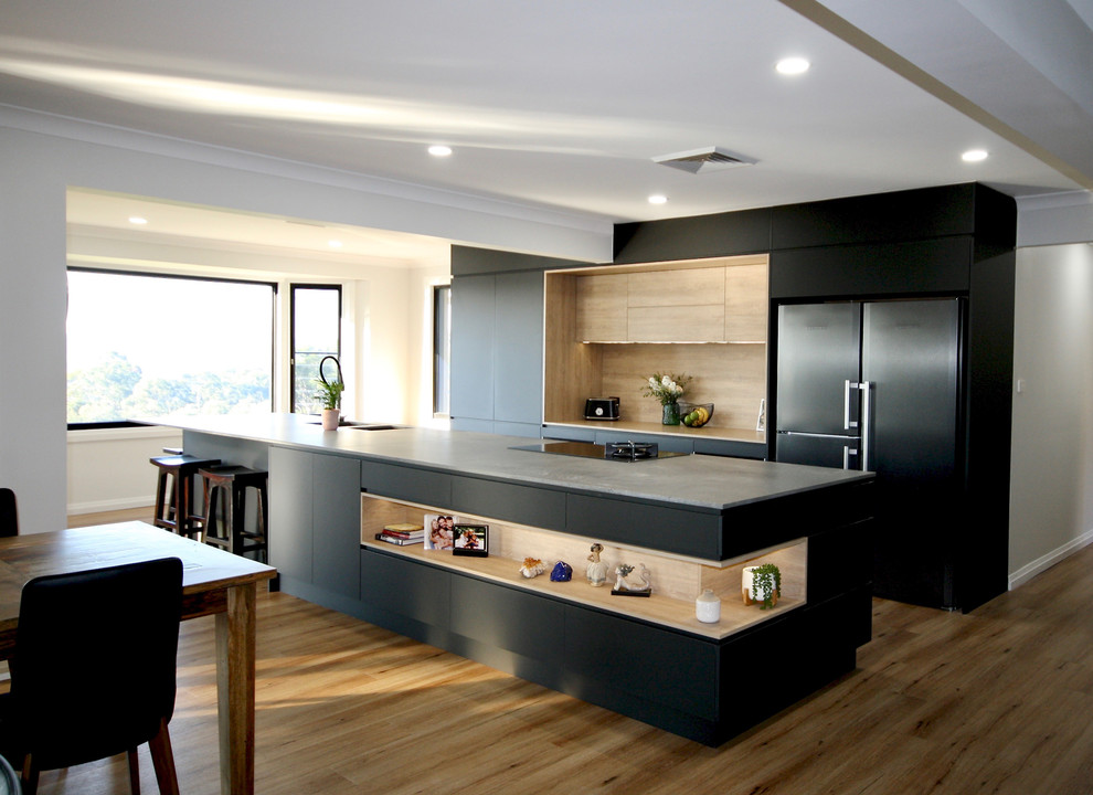 Esempio di una grande cucina moderna con lavello sottopiano, ante lisce, ante nere, top in quarzo composito, elettrodomestici neri, pavimento in legno massello medio, pavimento marrone e top grigio