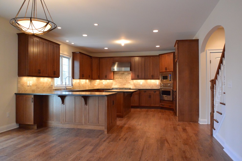 Cette image montre une grande cuisine chalet en bois brun avec un évier encastré, un placard à porte shaker, un plan de travail en granite, un électroménager en acier inoxydable, un sol en bois brun et îlot.