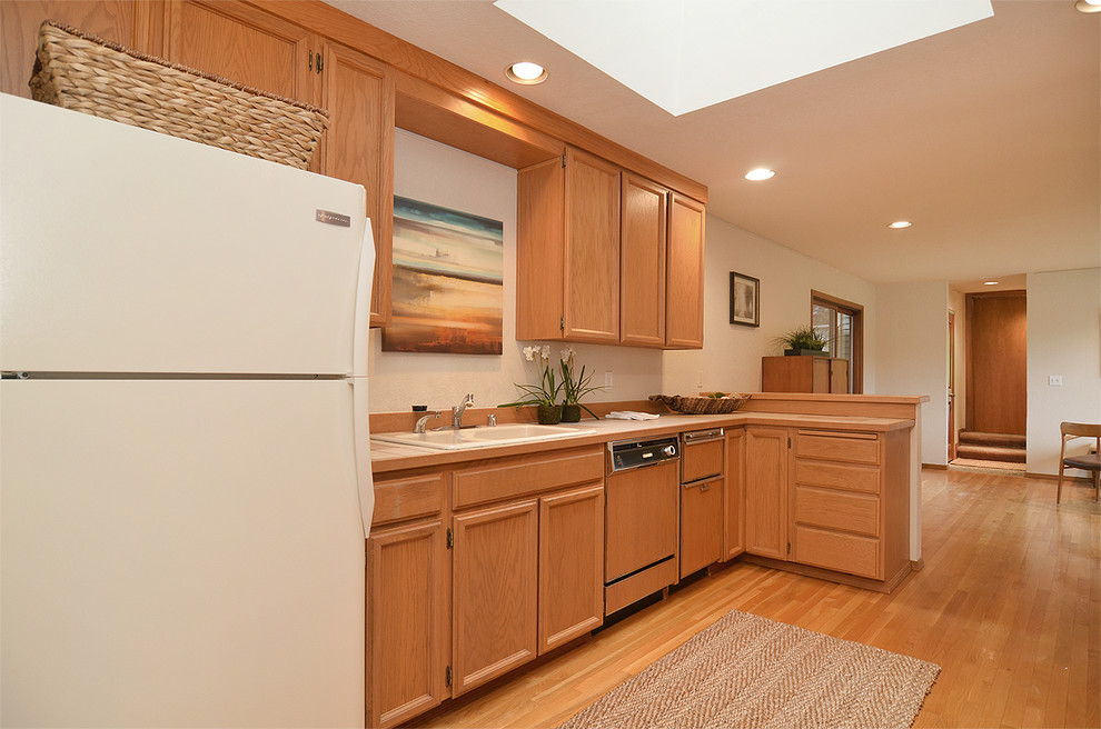 Mid-sized trendy l-shaped medium tone wood floor eat-in kitchen photo in Seattle with recessed-panel cabinets, tile countertops and an island