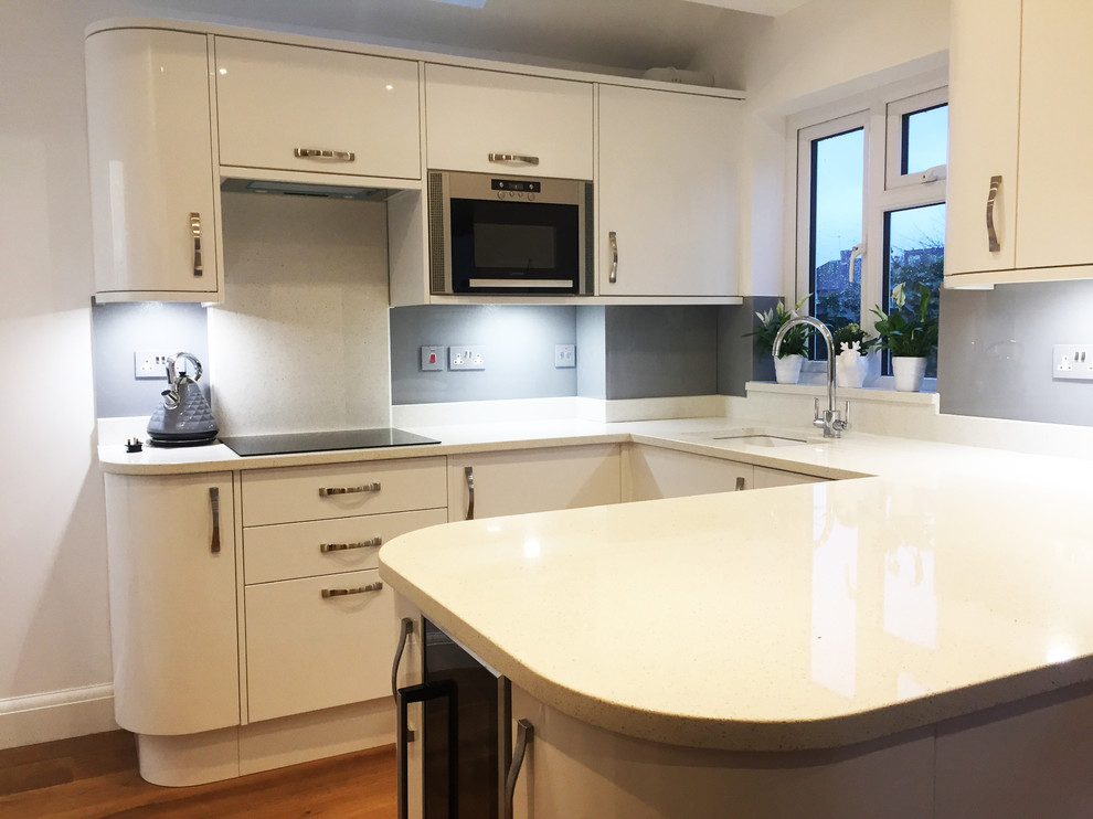 Photo of a large modern kitchen/diner in Hertfordshire with flat-panel cabinets, white cabinets, marble worktops, grey splashback and glass sheet splashback.