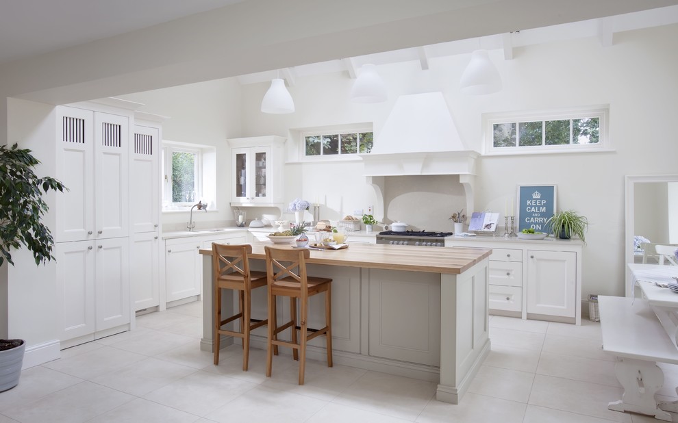 Example of a classic white floor kitchen design in Dublin with glass-front cabinets and wood countertops