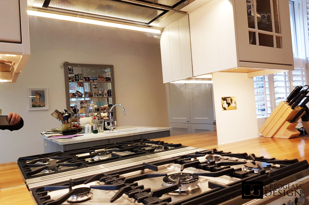 Immagine di una grande cucina abitabile minimalista con ante bianche, top in legno, paraspruzzi a effetto metallico, paraspruzzi a specchio, penisola e top marrone