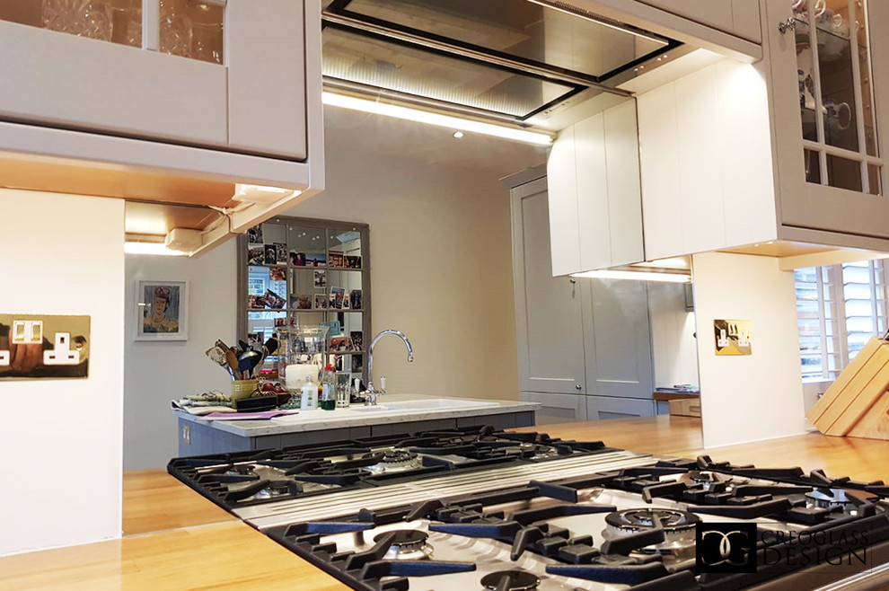 Foto di una grande cucina abitabile minimalista con ante bianche, top in legno, paraspruzzi a effetto metallico, paraspruzzi a specchio, penisola e top marrone