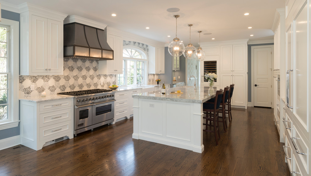 Example of a large trendy u-shaped medium tone wood floor and brown floor eat-in kitchen design in New York with recessed-panel cabinets, white cabinets, granite countertops, gray backsplash, stainless steel appliances, an island and an undermount sink